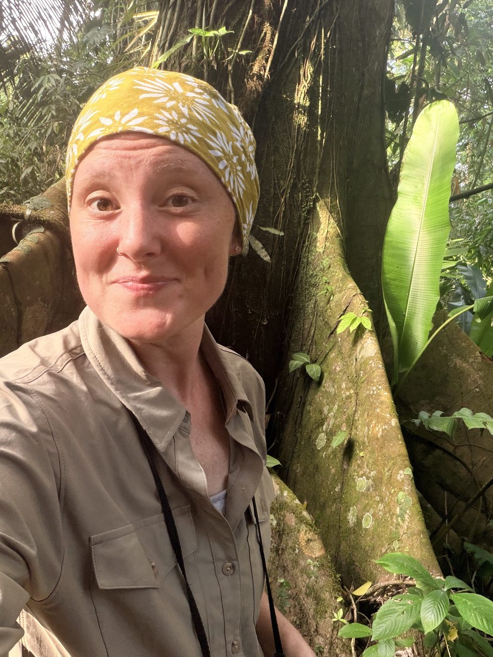Brittany in the Peruvian rainforest, smiling in front of a giant buttressed tree
