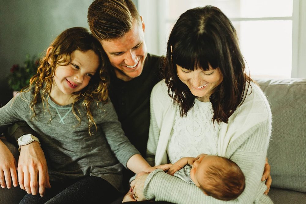 Brittany on the couch with her family, holding their newborn